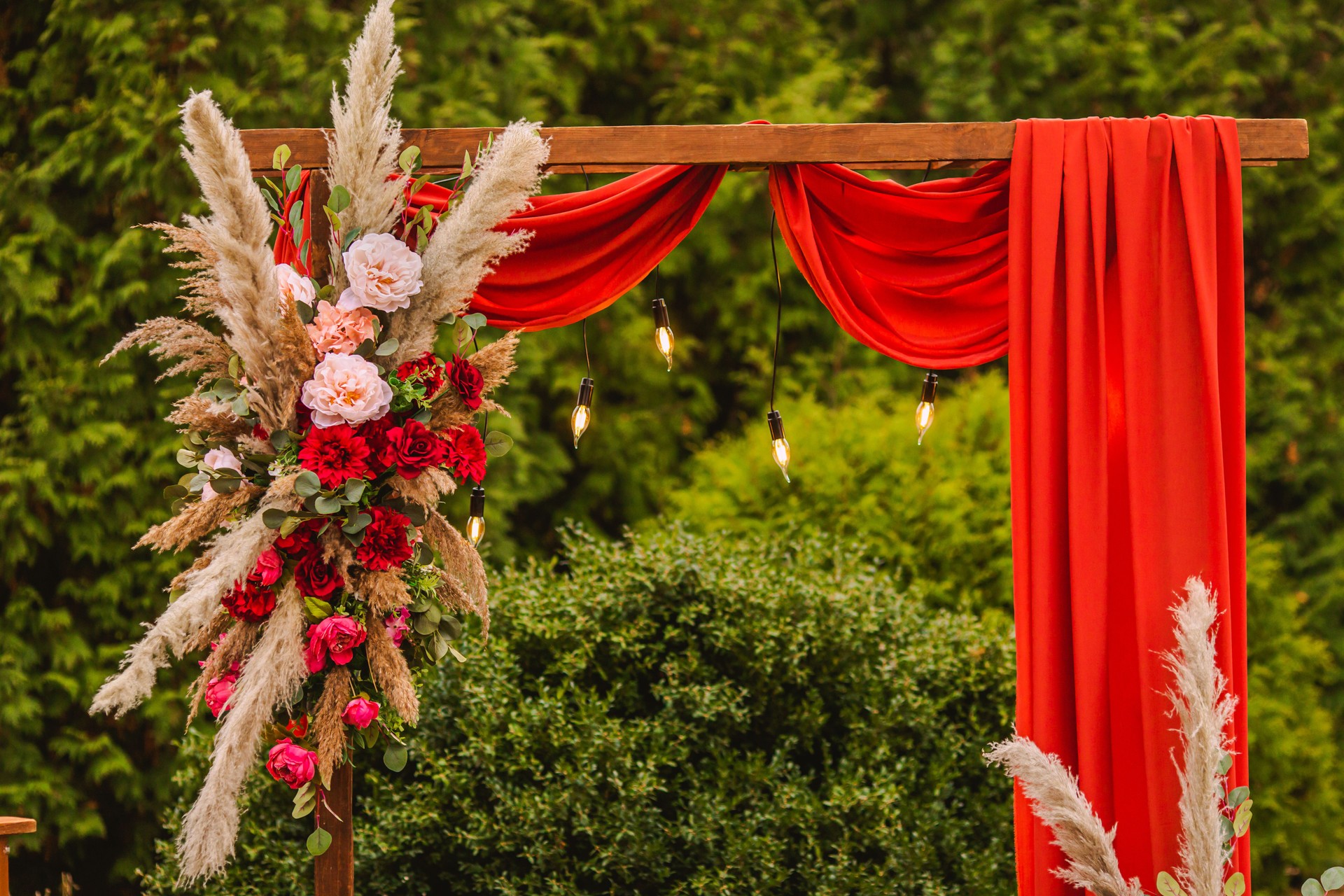 Wedding arch in boho style with flowers and light bulbs. Autumn wedding ceremony. Decor. Rustic